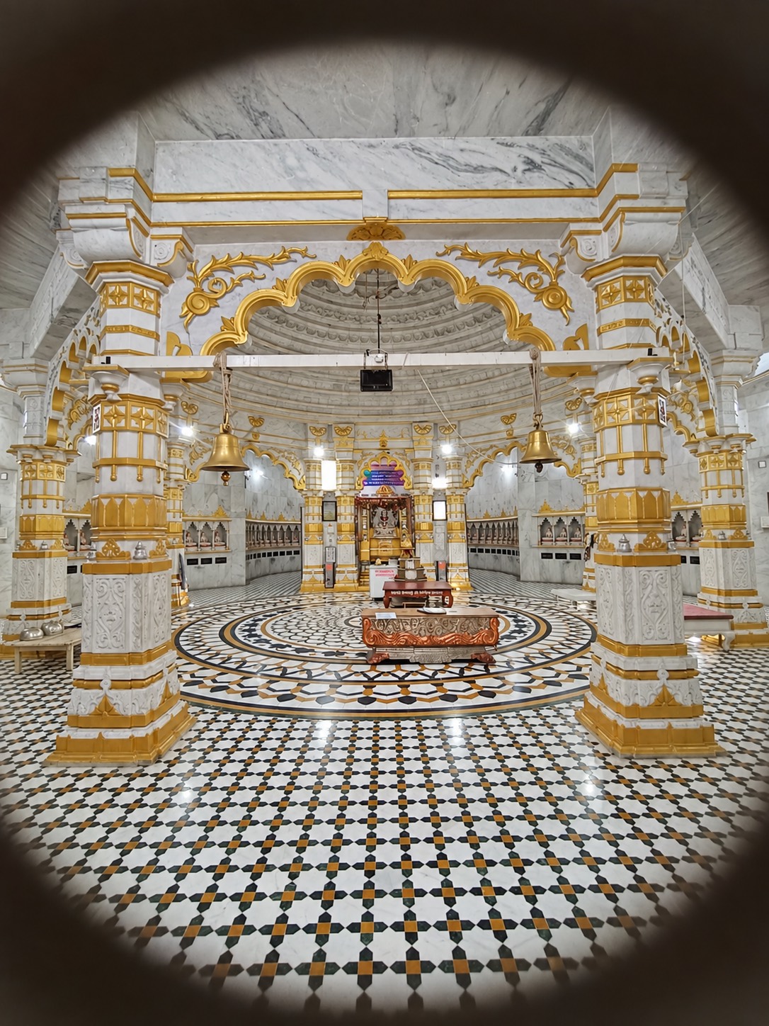 श्वेत-स्वर्णिम संगमरमर का मंडप, पीतल की घंटियाँ और तारक आकृति वाला जड़ाऊ फ़र्श